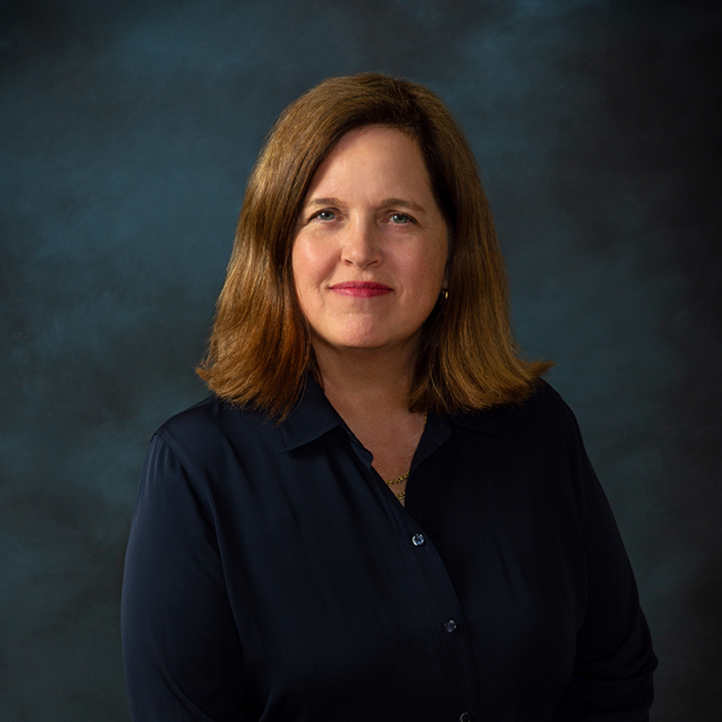 Photo of Contance Mazelsky seated in a blue shirt with a blue background.